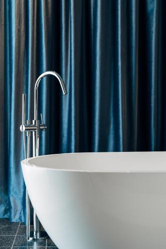 a white sink in a bathroom with a blue shower curtain at Hotel Galántha in Eisenstadt