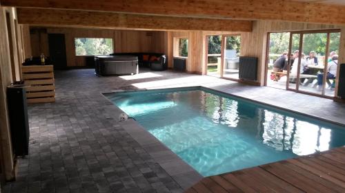 a large swimming pool in a house with people sitting at Auberge de la Fagne in Malmedy