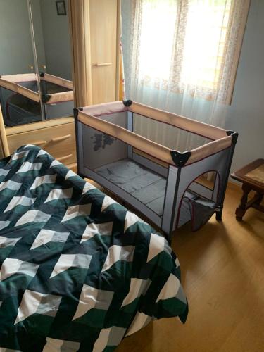 ein Babybett in einem Zimmer mit einem Bett in der Unterkunft Le Petit Logis entre Auvers et Paris in Montigny-lès-Cormeilles