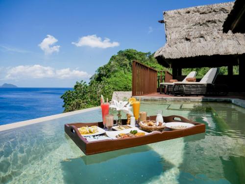 a tray of food on a swimming pool next to the ocean at Cauayan Island Resort and Spa in El Nido