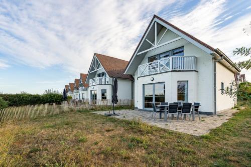 a white house with a table and chairs at Evancy Equihen-Plage in Équihen-Plage