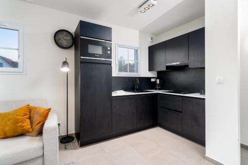 a kitchen with black cabinets and a clock on the wall at Evancy Equihen-Plage in Équihen-Plage