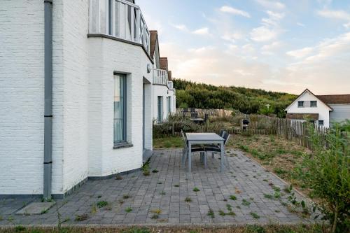 a table sits on a patio next to a white building at Evancy Equihen-Plage in Équihen-Plage