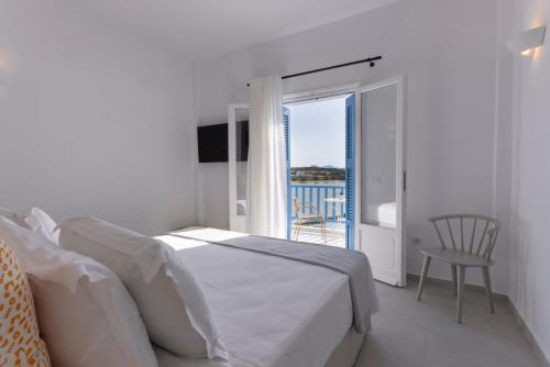 Habitación blanca con cama y balcón. en Kouros Village en Antiparos Town