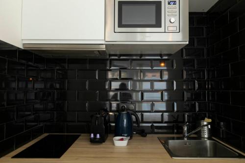 eine Küchentheke mit einer Spüle und einer Mikrowelle in der Unterkunft Studio moderne et confort au centre ville in Metz