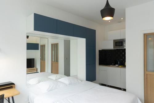 a bedroom with a white bed and a blue wall at Studio moderne et confort au centre ville in Metz
