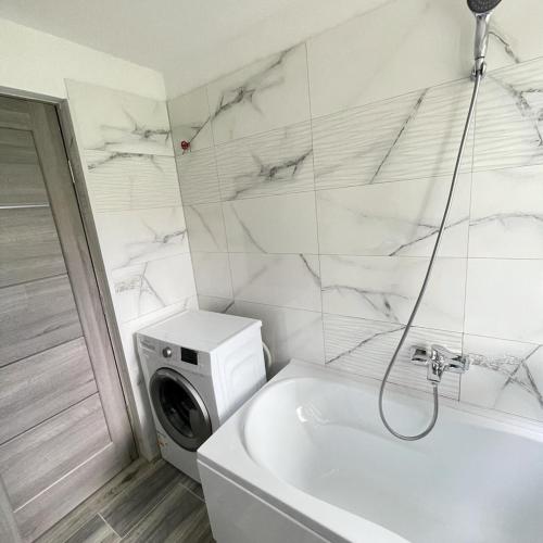 a bathroom with a tub and a washing machine at Garsoniera Brasov zarnesti in Zărneşti