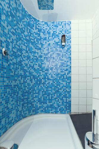 a blue tiled bathroom with a white tub and blue tiles at Apartments im Einhornhaus in Lübeck