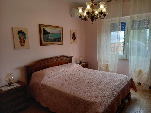 1 dormitorio con cama y lámpara de araña en Casa Blu oltremare, en SantʼAntìoco