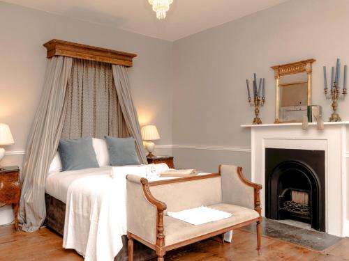 um quarto com uma cama com lareira e uma cadeira em Pass the Keys Elegant Georgian Townhouse in the heart Bath em Bath