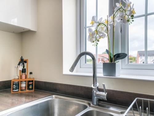 a kitchen sink with a vase of flowers in a window at Pass the Keys Stylish modern two bedroom home in Shrewsbury in Shrewsbury