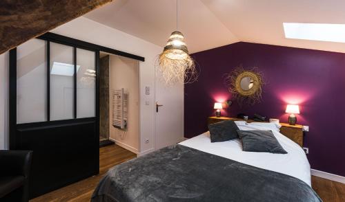 - une chambre avec des murs violets et un grand lit dans l'établissement Les Gîtes du château - L Appartement du Roi - Magnifique Appartement face au château, à Nérac