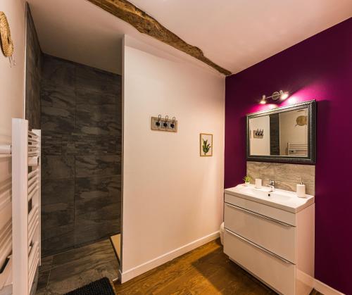 La salle de bains est pourvue de murs violets et d'un lavabo. dans l'établissement Les Gîtes du château - L Appartement du Roi - Magnifique Appartement face au château, à Nérac