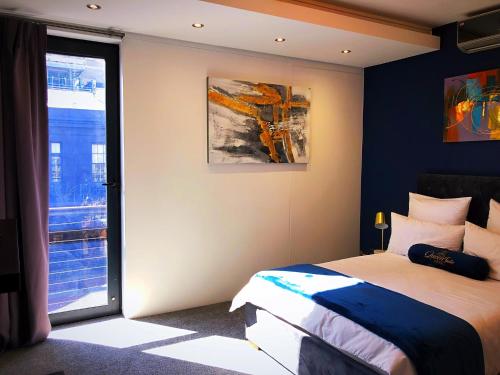 sypialnia z łóżkiem i dużym oknem w obiekcie Queen Julie Lodge w Kapsztadzie