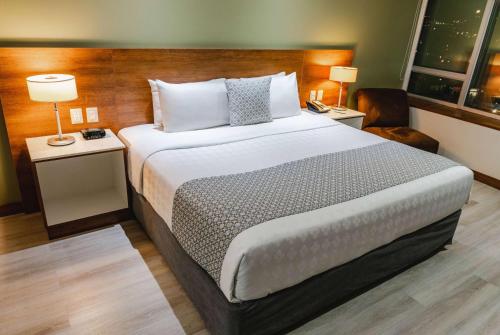 a bedroom with a large bed with two tables and two lamps at Wyndham Garden Guayaquil in Guayaquil