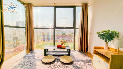 a living room with a table and a large window at Libré Homestay in Hanoi