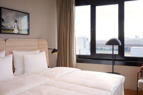 a bedroom with a large white bed with windows at Scandic München Macherei in Munich