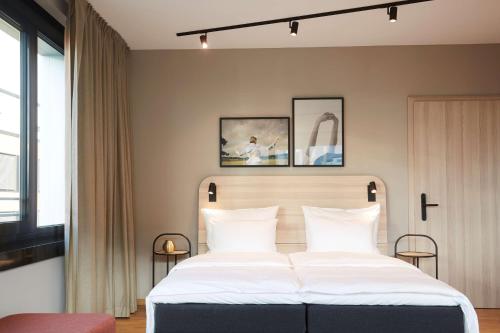 una camera da letto con un grande letto con cuscini bianchi di Scandic München Macherei a Monaco