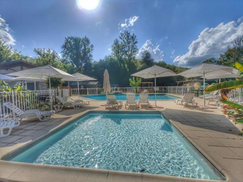 a swimming pool with chairs and umbrellas at hôtel gites le clos du moulin in Terrasson-Lavilledieu