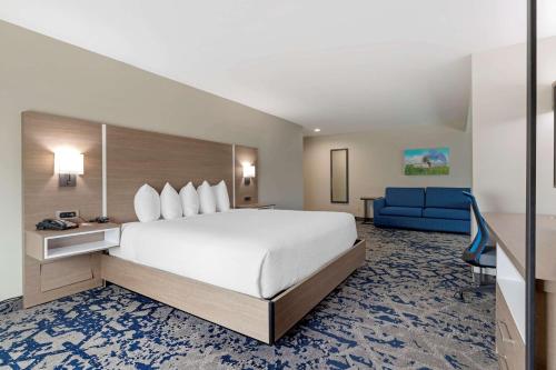 Cette chambre comprend un grand lit et un canapé bleu. dans l'établissement Comfort Inn & Suites, à Muskogee