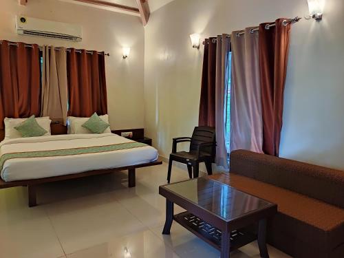 a room with a bed and a couch and a table at Cocorico Beach Resort in Dapoli