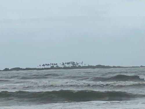 a body of water with waves and trees in the background at Rock n Ocean 2BH Beach villa island Facing in Udupi