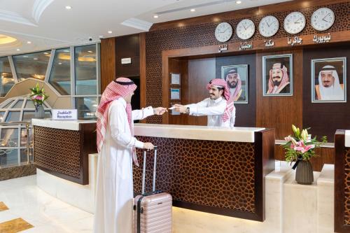 two women standing at a counter in a hotel lobby at MADEN Hotel in Al Madinah