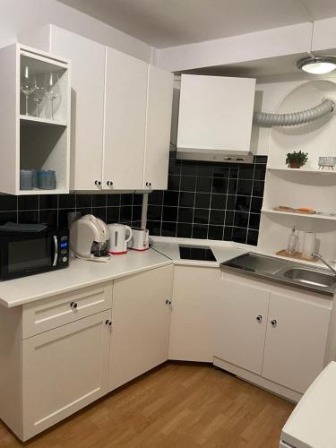 una cocina con armarios blancos y una pared de azulejos negros en Appartement a Paris en París