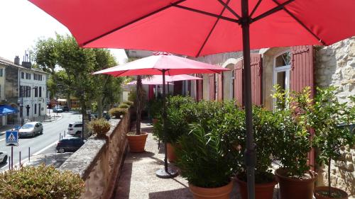 two red umbrellas and potted plants on a sidewalk at Hotel Des Artistes in Tarascon