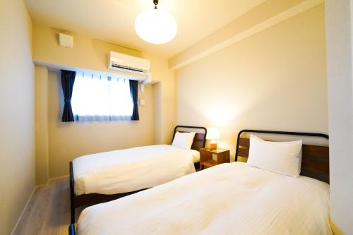 two beds in a small room with a window at Branchera Naha 1107 in Naha