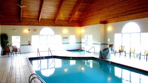 een groot zwembad in een gebouw met stoelen bij Country Inn River Falls in River Falls
