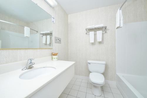 Baño blanco con lavabo y aseo en Travelodge by Wyndham Great Barrington Berkshires, en Great Barrington