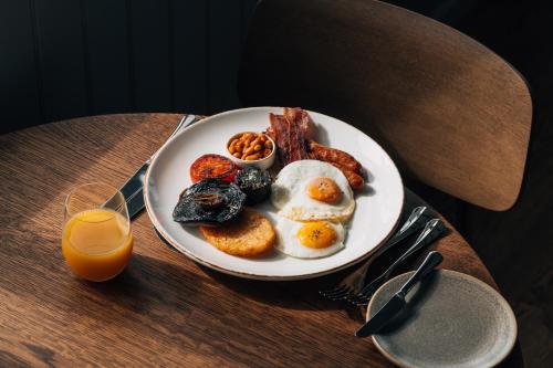 a plate of breakfast food on a table with orange juice at The Sparsholt Barn in Wantage