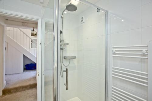 a glass shower in a bathroom with a staircase at The Mews, Tresean in Newquay