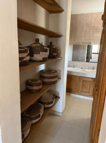 a kitchen with wooden shelves with baskets and a sink at Appartement "AMINA" - Ihr stilvolles Zuhause in Saly Portudal in Saly Portudal