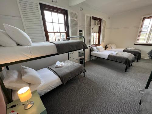 a room with three bunk beds and a lamp at Hotel Concord in Sydney