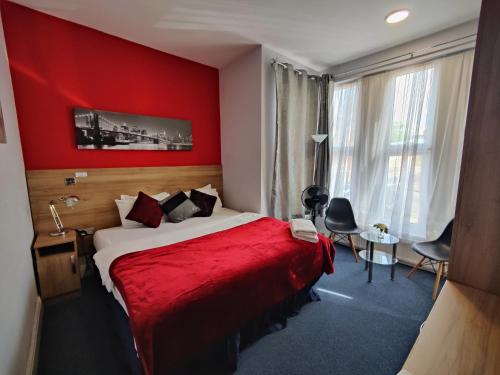 a red room with a bed with a red wall at Wellesley Hotel in Ilford
