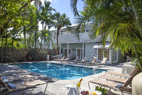 a swimming pool with chairs and a house at Southernmost Inn Adult Exclusive in Key West