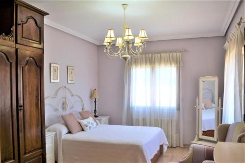 um quarto com 2 camas e um lustre em 5 bedrooms villa with private pool jacuzzi and enclosed garden at Fernan Caballero em Fernancaballero