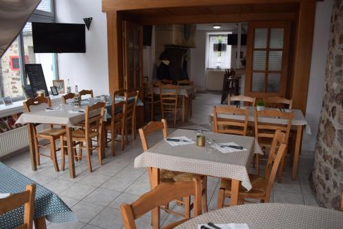 un comedor con mesas y sillas en un restaurante en Auberge de la vallée de la douve, en L'Etang-Bertrand