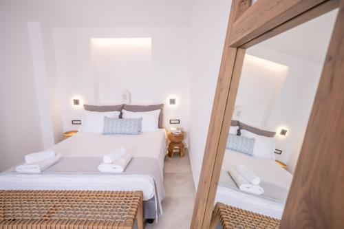 a bedroom with two beds and a mirror at Kouros Village in Antiparos