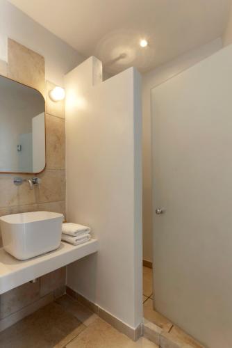 a bathroom with a white sink and a mirror at Kouros Village in Antiparos Town