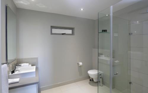 a bathroom with a toilet and a glass shower at The Capital on Bath in Johannesburg