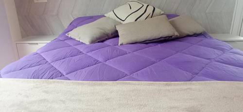 a purple comforter and pillows on a bed at DÚPLEX ÁTICO XANA FOZ con terraza 80 m2 privada y vistas a la ría in Foz