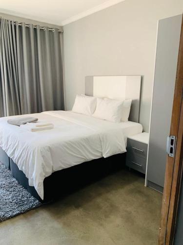 a bedroom with a large white bed and a window at Alu Boutique Hotel and Conference in Roodepoort