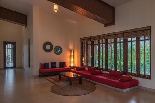 a living room with a red couch and a table at SaffronStays Ananya, Karjat in Karjat