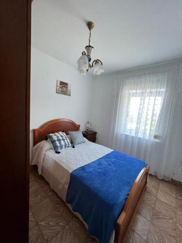 a bedroom with a bed with a blue blanket and a window at Casa Balteiro in Cedeira