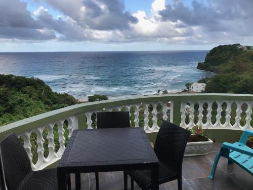 a balcony with a table and chairs and the ocean at I VIEW - in Long Bay in Port Antonio