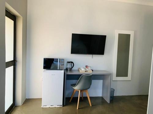 a desk with a refrigerator and a chair in a room at Alu Boutique Hotel and Conference in Roodepoort