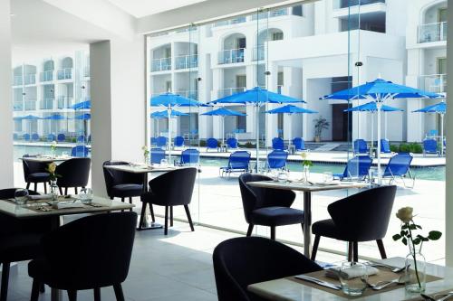 a restaurant with tables and chairs and blue umbrellas at Pickalbatros Blu Spa Resort - Adults Friendly 16 Years Plus- Ultra All-Inclusive in Hurghada
